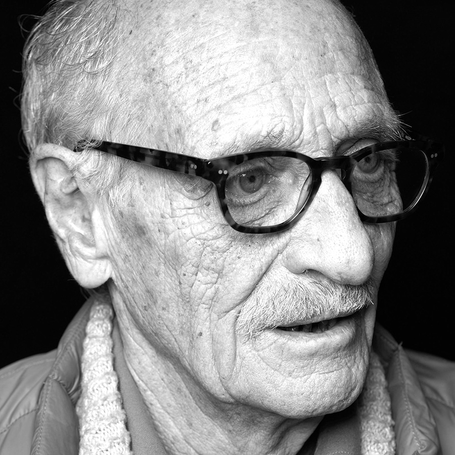 An old man wearing glasses, in black and white