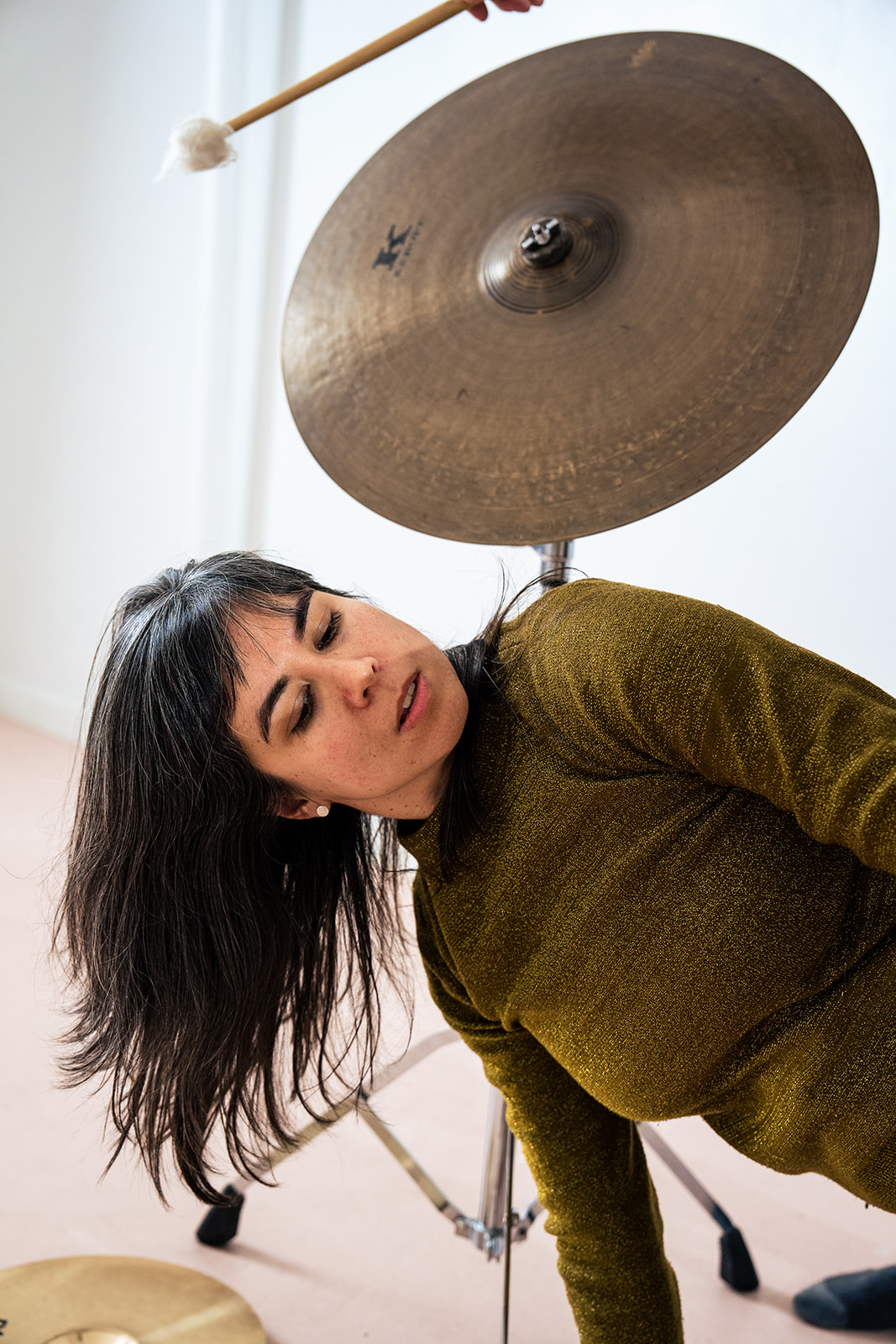 A woman leans sideways underneath a cymbal