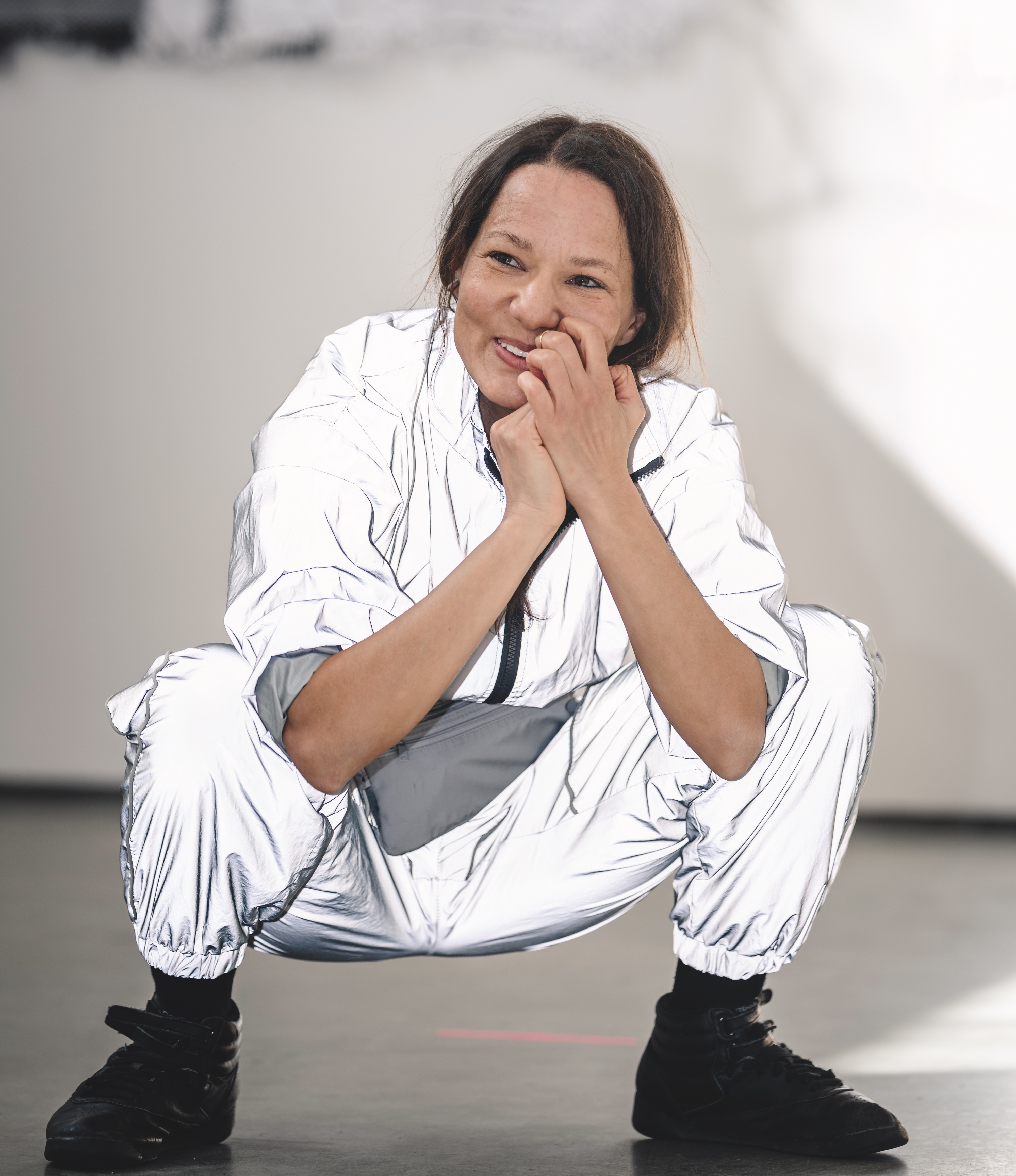 A women in a white jump suit is crouched smiling