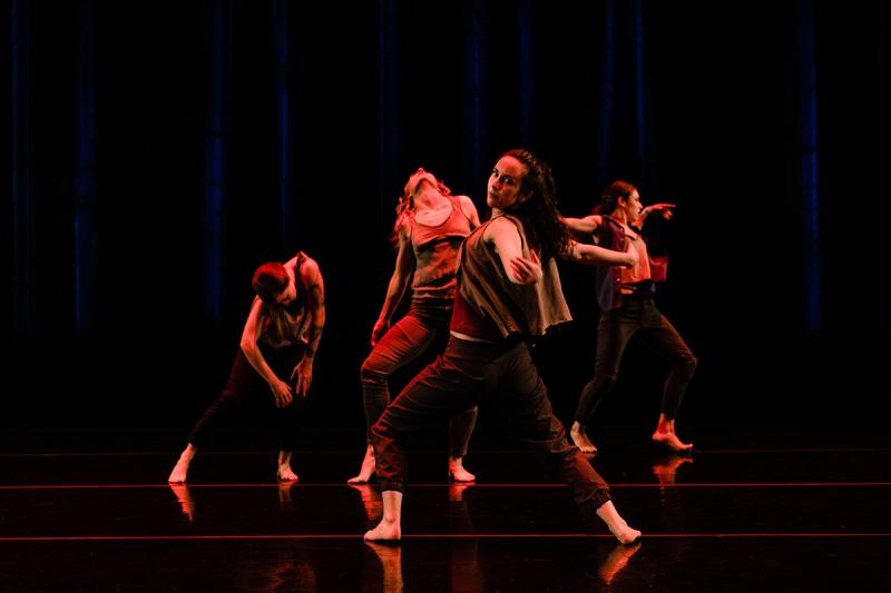 Dancers in red light reaching to camera