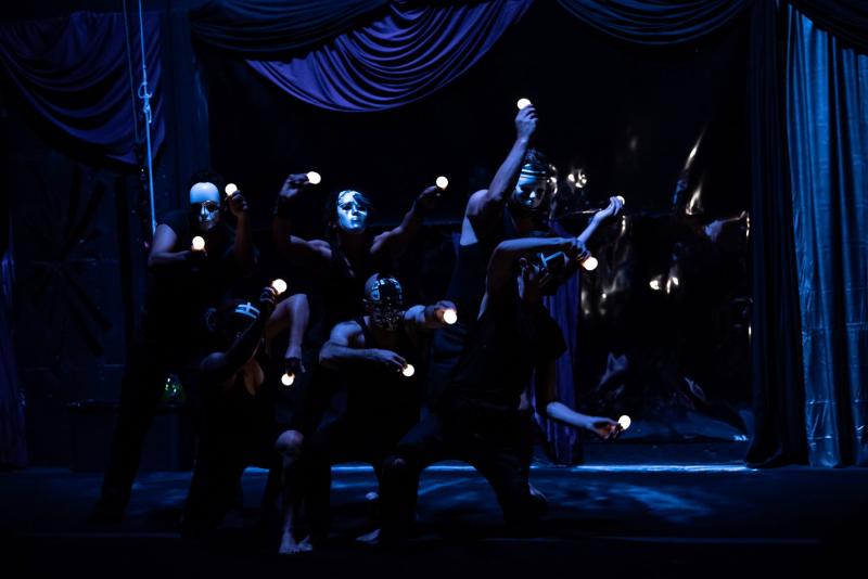 A photo of a group of people wearing white and black masks and hodling lightbulbs.