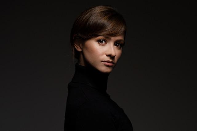 A photo of a woman in a black turtleneck with dark brown hair.