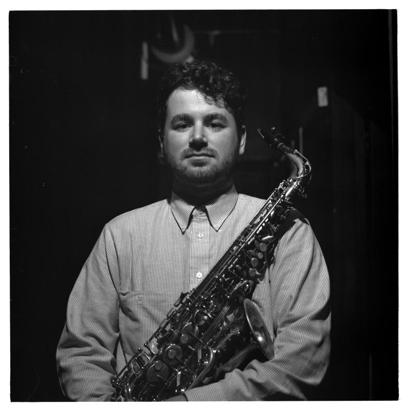 A black and white photo of a man holding a saxophone