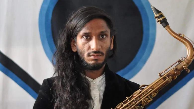 A person stands with a saxophones