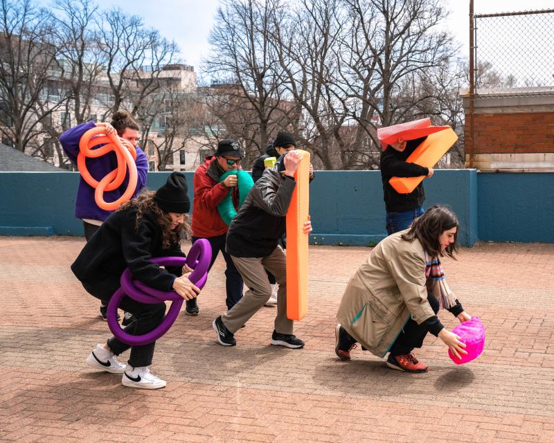 A group of people walk carrying neon coloured plush objects.