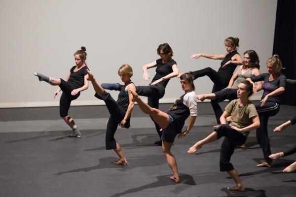 A group of dancers leaning back and leg extended high