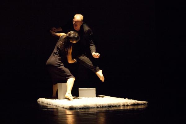 dancers stepping over box in dim light