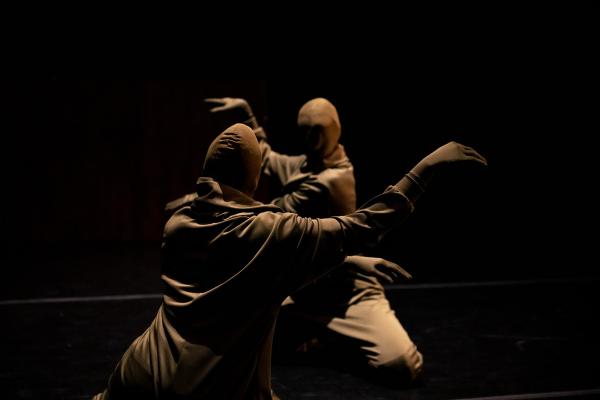 An image of two people kneeling on the floor in dark green suits with masks and gloves