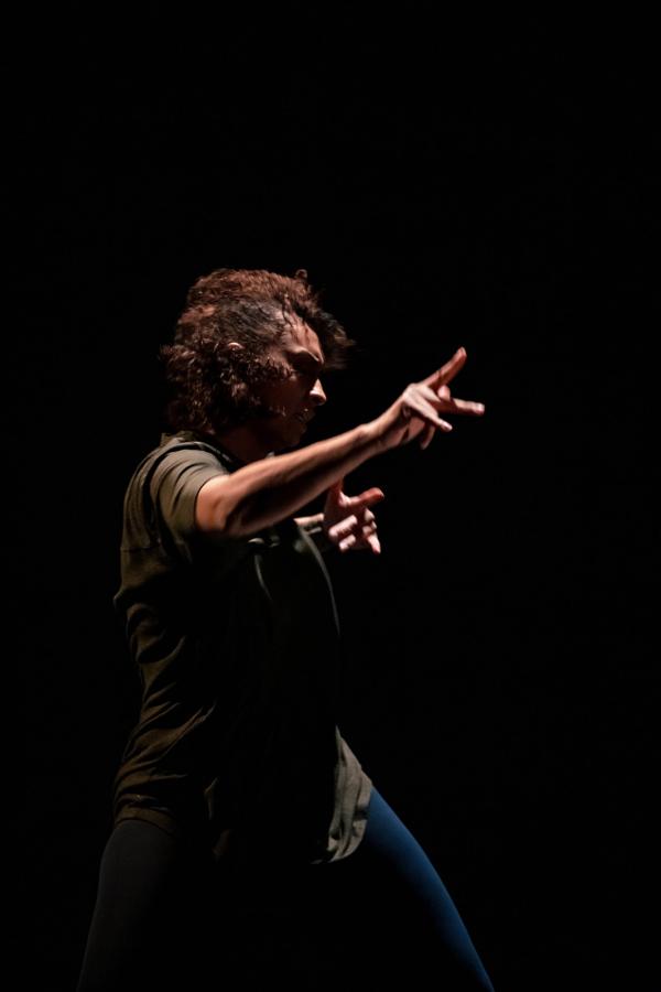 A photo of a person with dark curly hair caught in a fast gesture