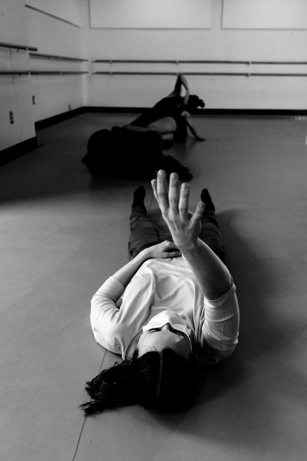 A black and white image of three dancers in various shapes on the floor.