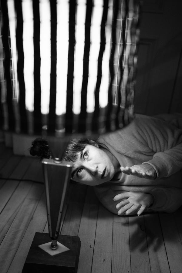 A woman lays on the ground looking up at a lamp with a striped lampshade.