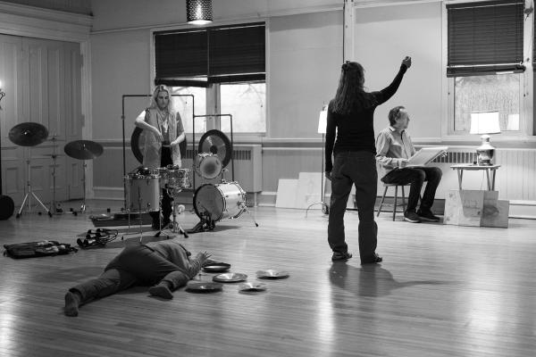 Four people are spread out in a room with many percussion instruments