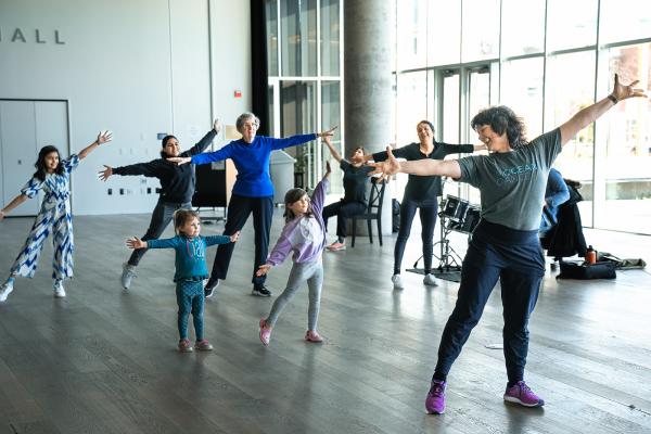 A group of people dance in a bright room.