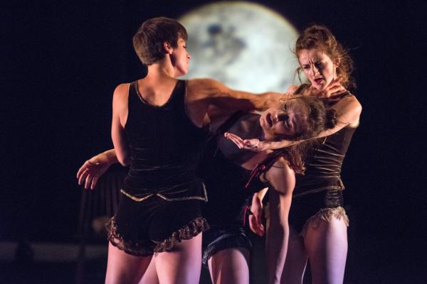 Three dancers move in front of backdrop of a night sky and moon.