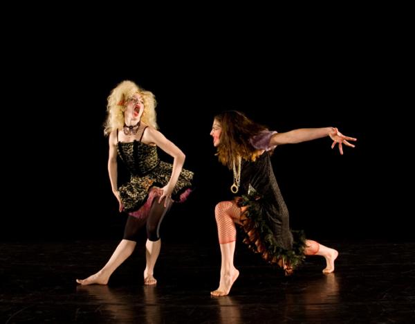 Two dancers face each other in poses. 