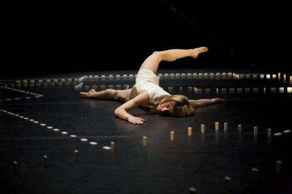 A woman dances on the floor, inside a border of dominos.