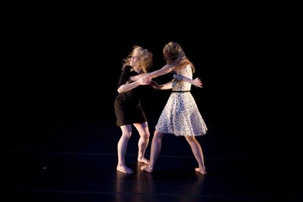 Two dancers face each other in motion.