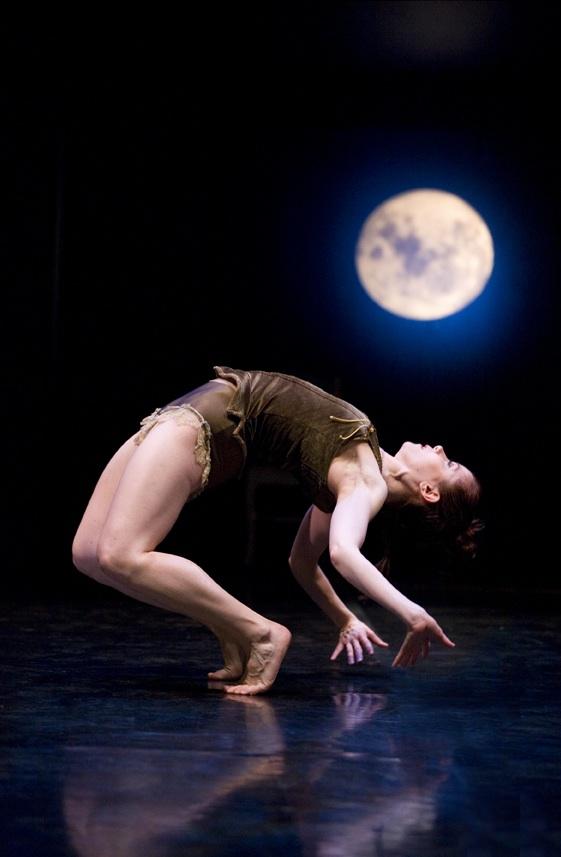 A dancer in a backbend in front of backdrop of a night sky and moon. 