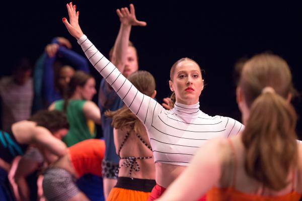 A group of people in colourful clothes dance in a line.