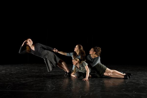 One dancer leans away from three dancers sitting on the floor. 