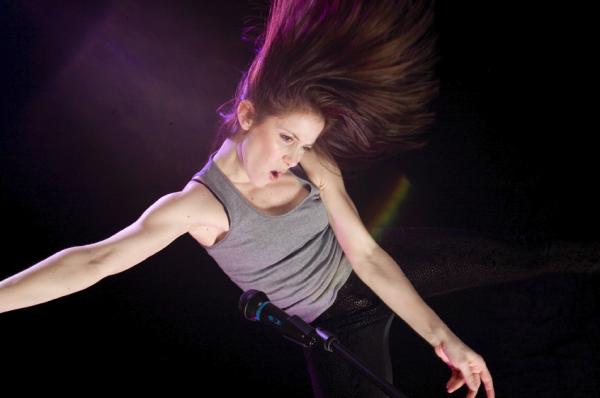 A dancer moves in front of a microphone. 