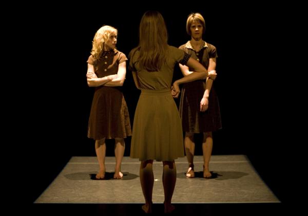 One dancer faces the back toward two other dancers. 