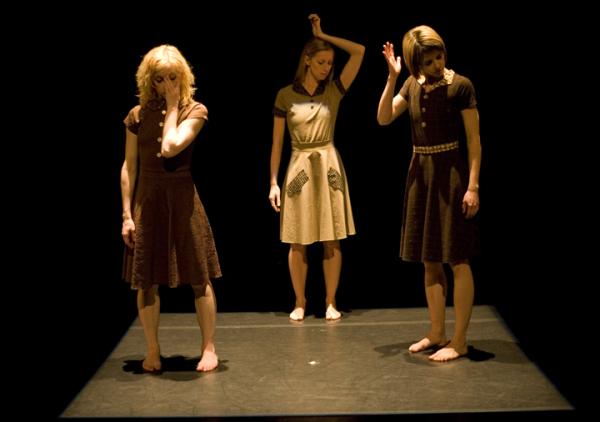 Three dancers stand with one hand hovering near their faces. 