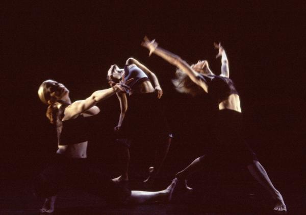 Three dancers take different shapes in front of a black backdrop. 