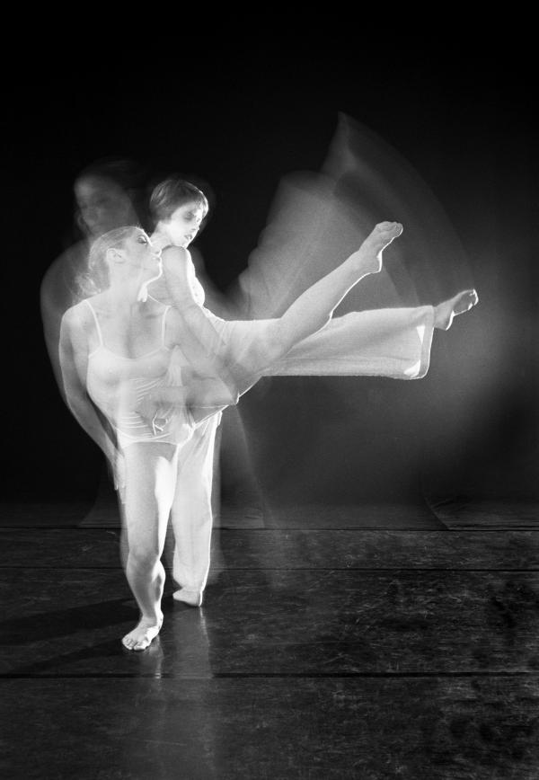 Two dancers extend their legs to the side in a blurred image. 