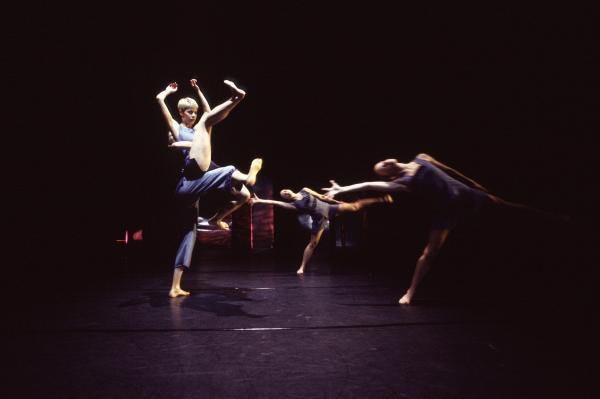 4 dancers move in front of a black backdrop.