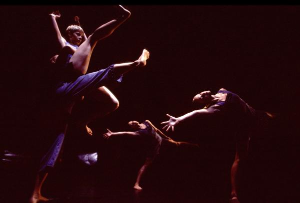 4 dancers move in front of a black backdrop.