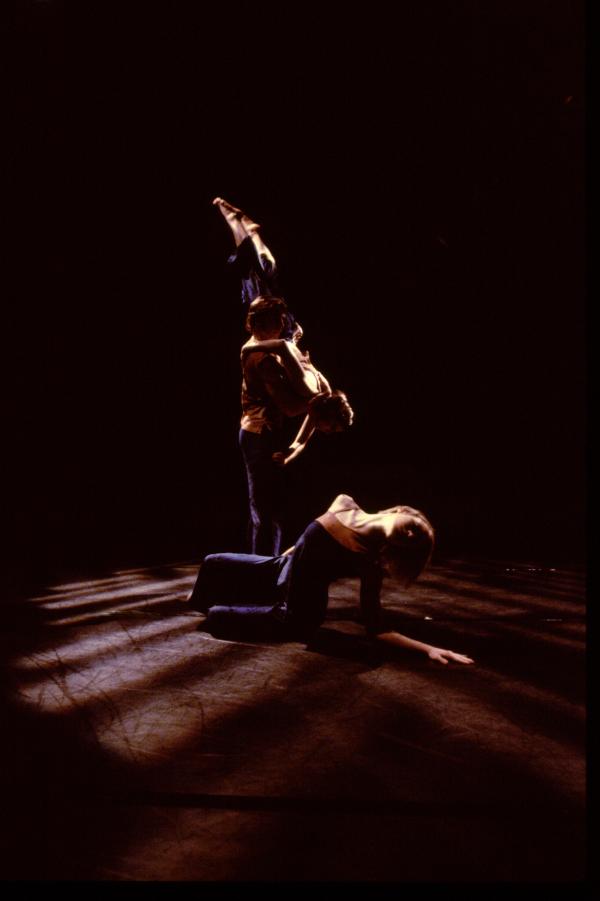 A duet moves behind a dancer sitting on the ground. 