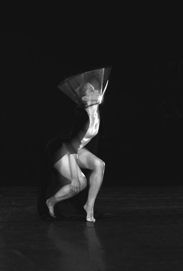 A dancer wears high heels and a transparent cone around her head. 