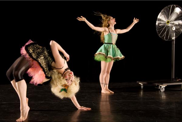 Two dancers on stage with a fan