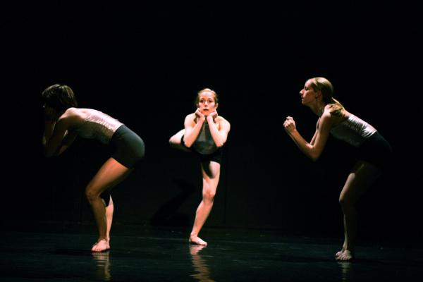 Three dancers stand on one leg. 