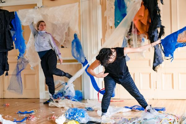 Two people dance in a room full of plastic debris.