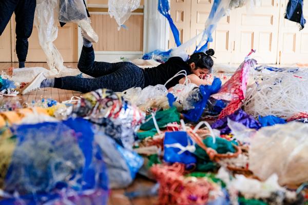 A woman rolls on a floor covered in plastic debris