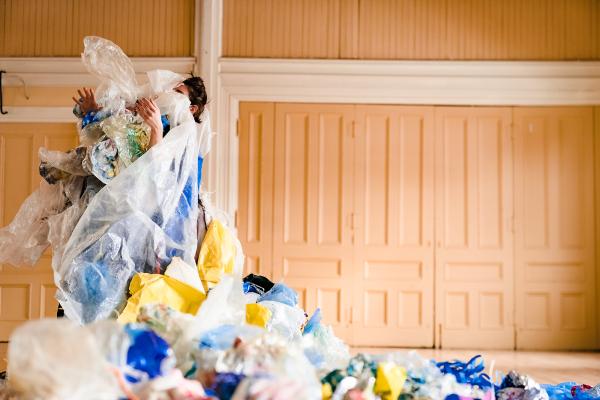 A person stands covered in plastic debris