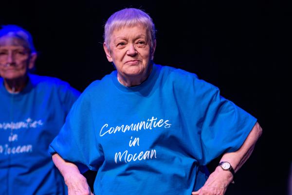 an older adult in a blue t-shirt with hands on hips looking out smiling