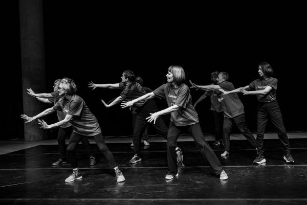 Group of elderly dancers in blue shirts against black background in free flow dance party energy