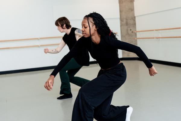 Two people dance in a white studio