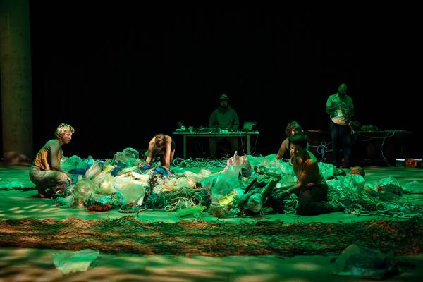 Multiple people crouched dancing in plastic debris