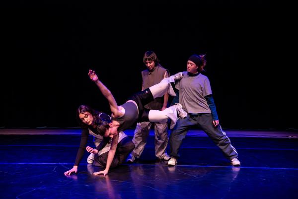 Three dancers help balance another dancer in the air