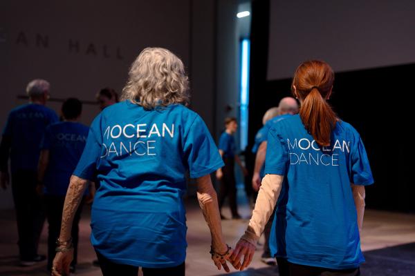 Two women in blue t-shirts hold hands