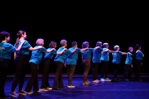 A group of dancers holding the shoulder of another