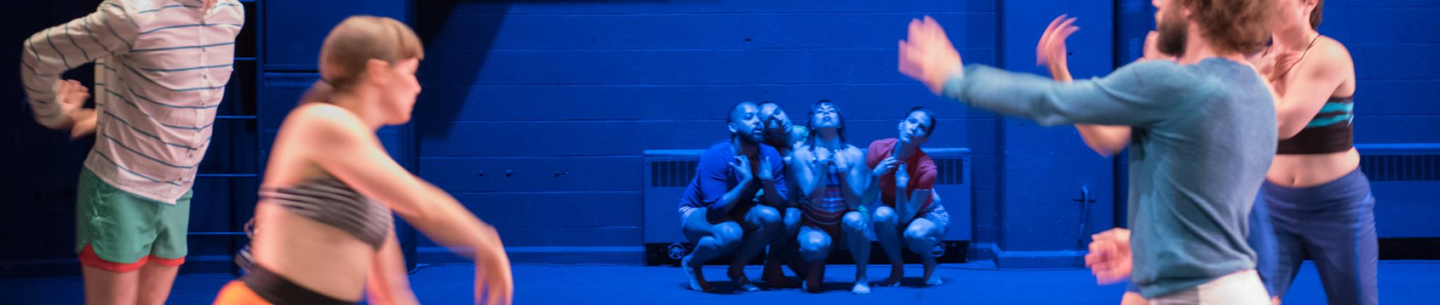 One group of dancers move in the foreground, while another group huddles low in the background.