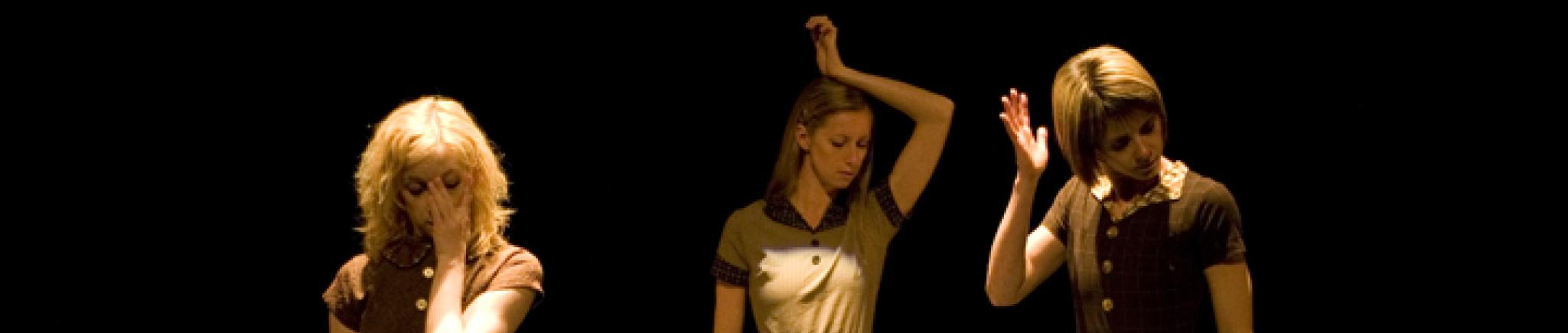 Three dancers stand with one hand hovering near their faces. 