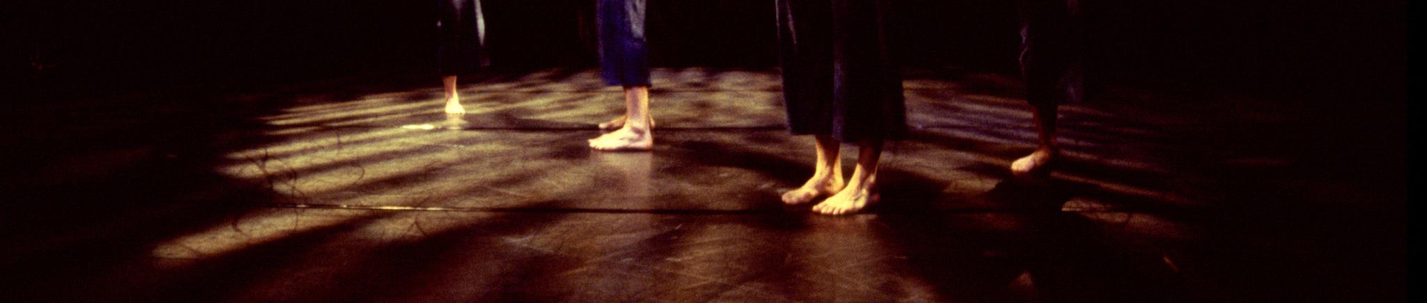 Five dancers move in front of a black backdrop. 