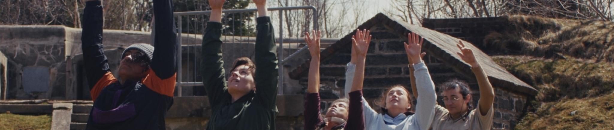 Five dancers in a line with their hands raised