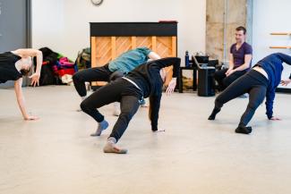 4 dancers on the ground arched back with a leg extended